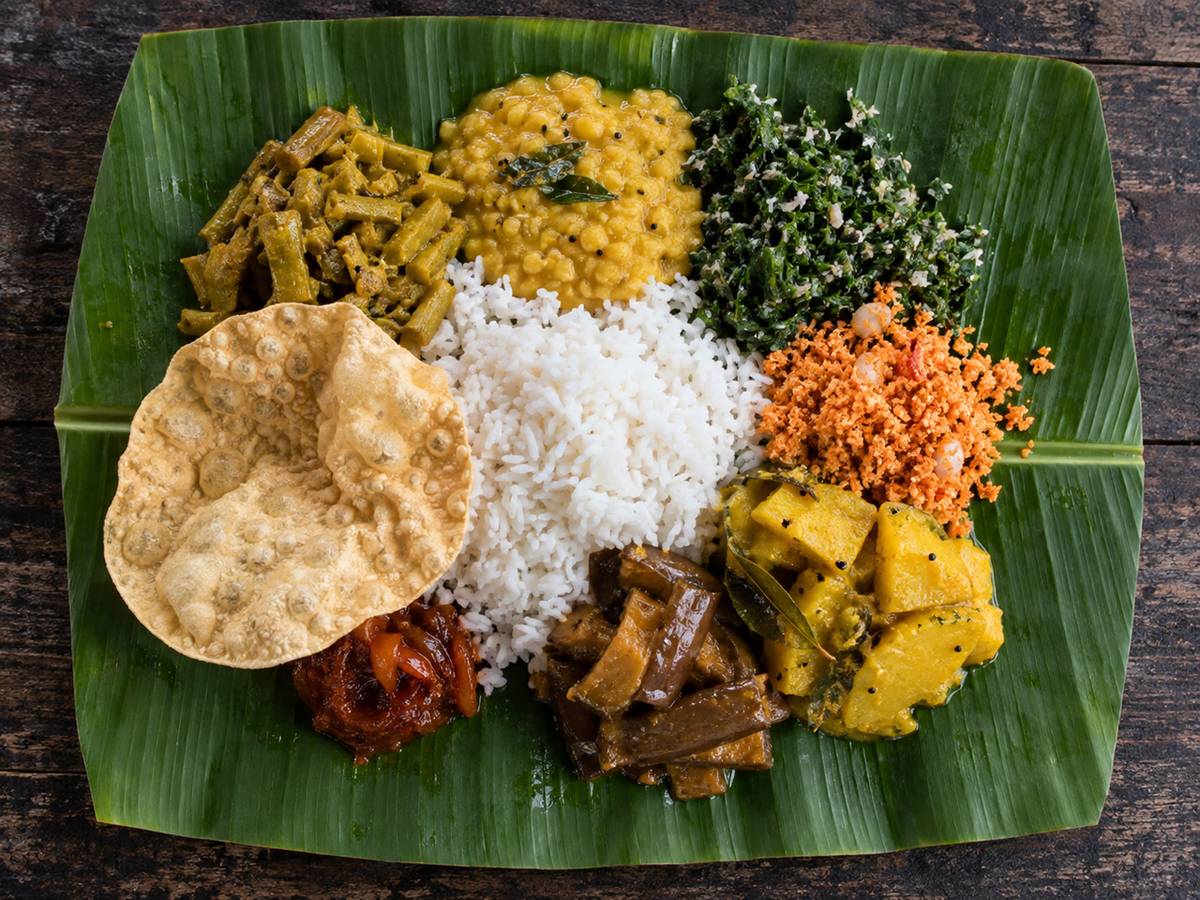 Overhead banana-leaf plate with several vegetable curries and pol sambol